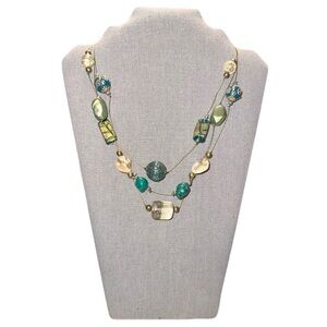 Multi-strand necklace featuring large, varied beads in shades of green, blue